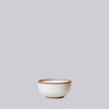 White ceramic bowl with brown rim on a light gray background