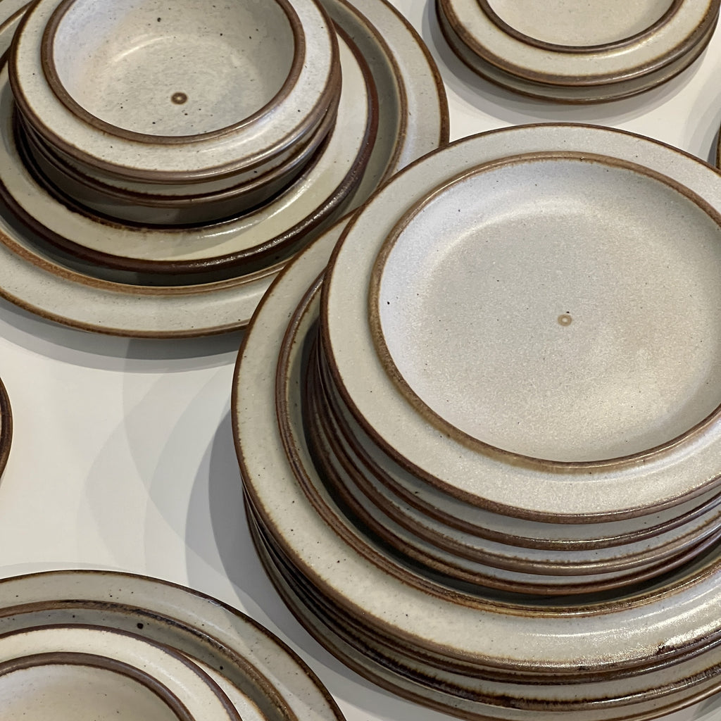 Stacks of ceramic plates with brown rims on a white surface