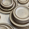 Stacks of ceramic plates with brown rims on a white surface