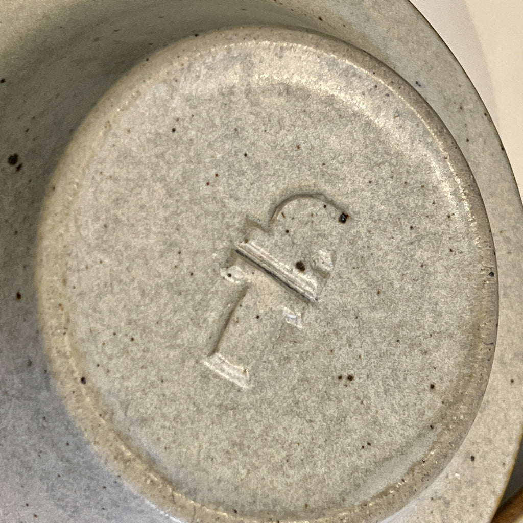 Close-up of a ceramic plate with a logo on a beige background