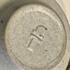 Close-up of a ceramic plate with a logo on a beige background