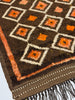 Close-up of a patterned rug with brown, orange, and white colors.