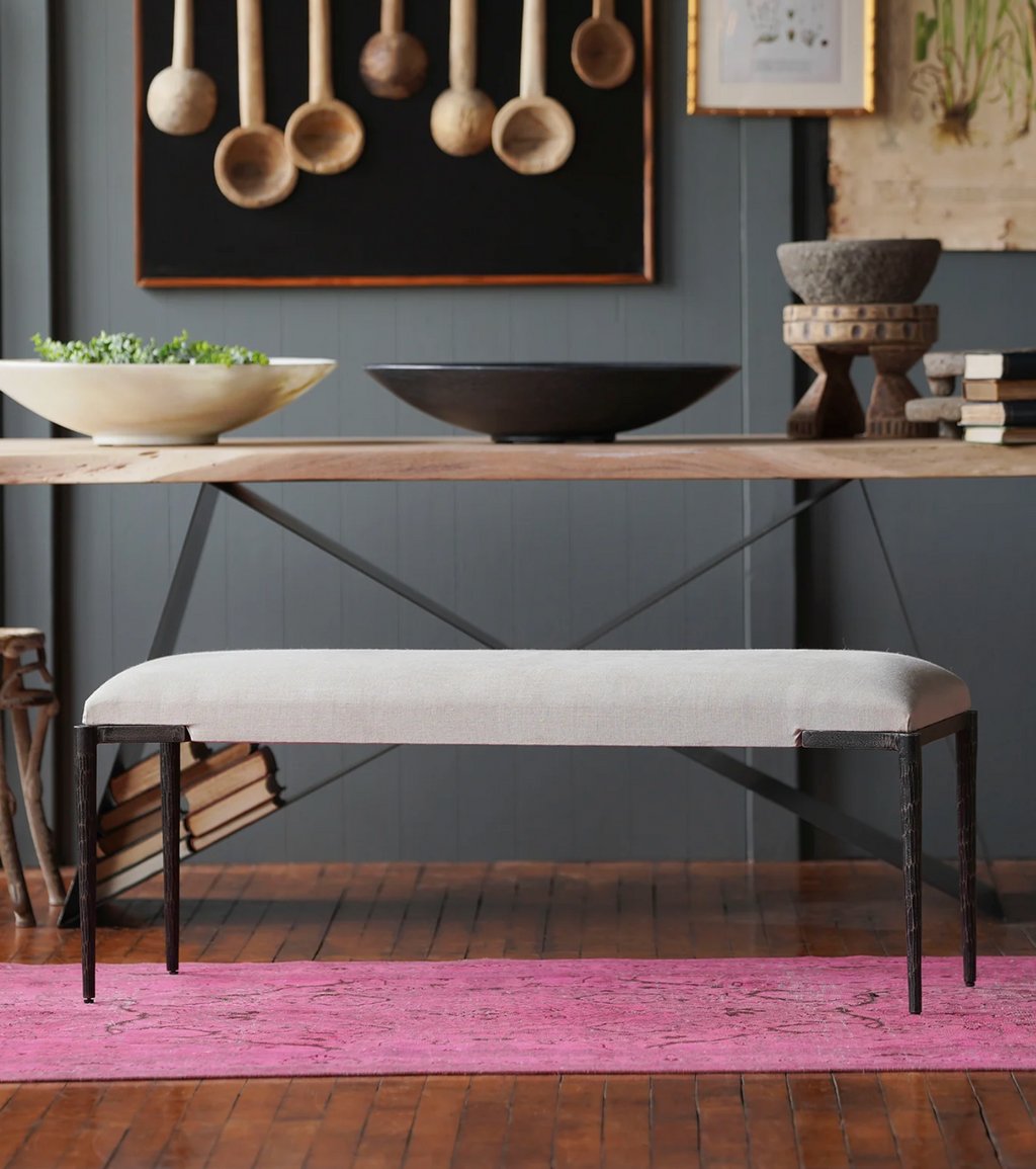 Dining room with wooden table, gray bench, and decorative items on a dark gray wall.