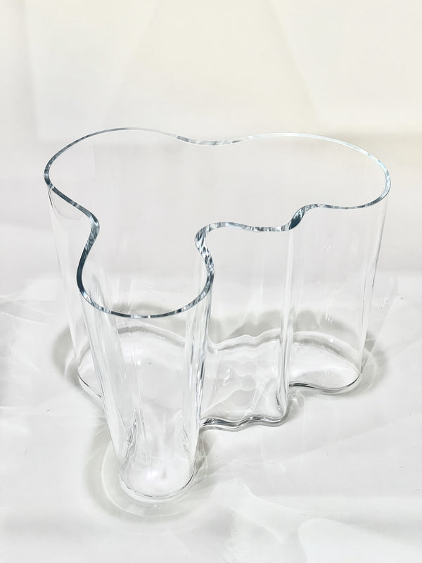 Clear glass vase with a unique, organic shape on a white background