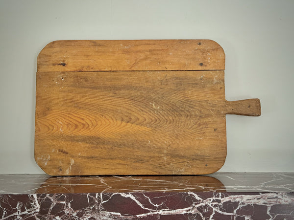 Wooden cutting board with a handle on a marble surface