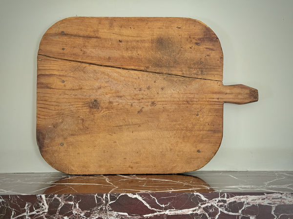Old wooden cutting board with a handle on a marble surface