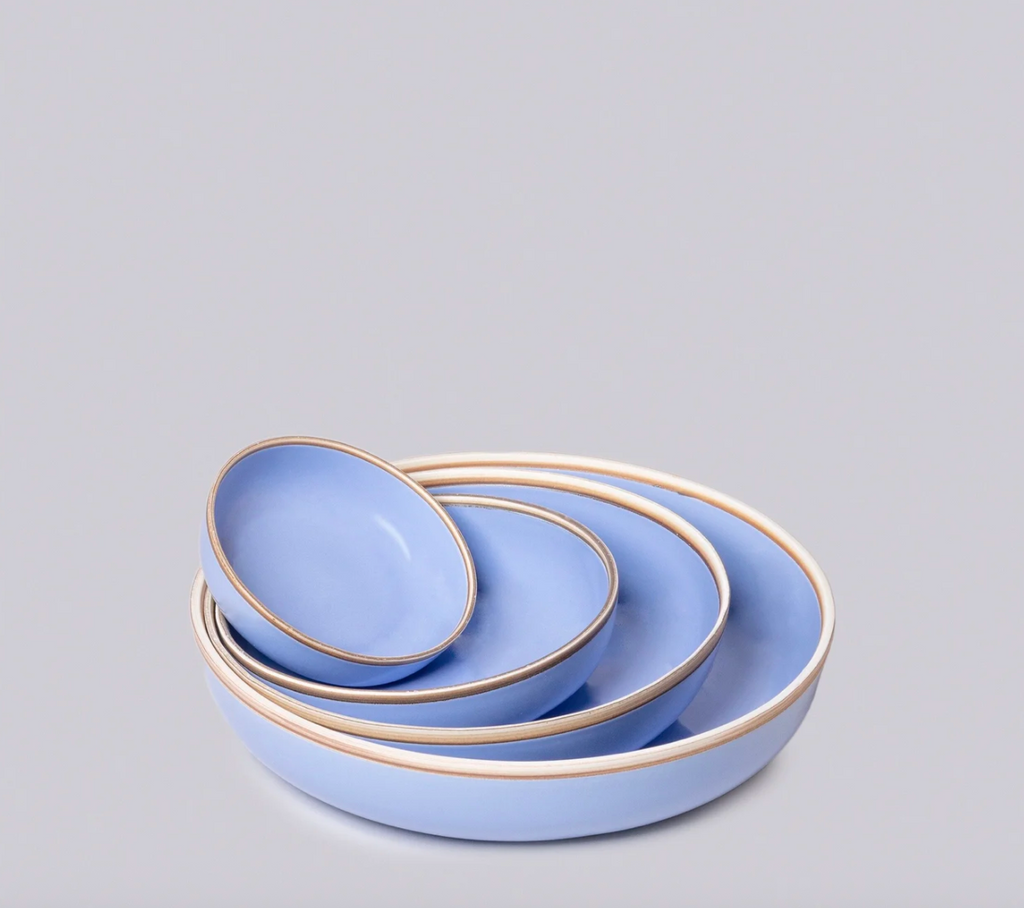 Set of three light blue ceramic bowls with gold rims on a gray background