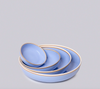 Set of three light blue ceramic bowls with gold rims on a gray background