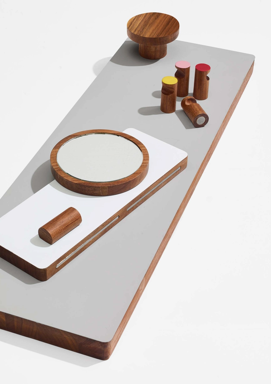 Wooden hooks and mirror on a white surface