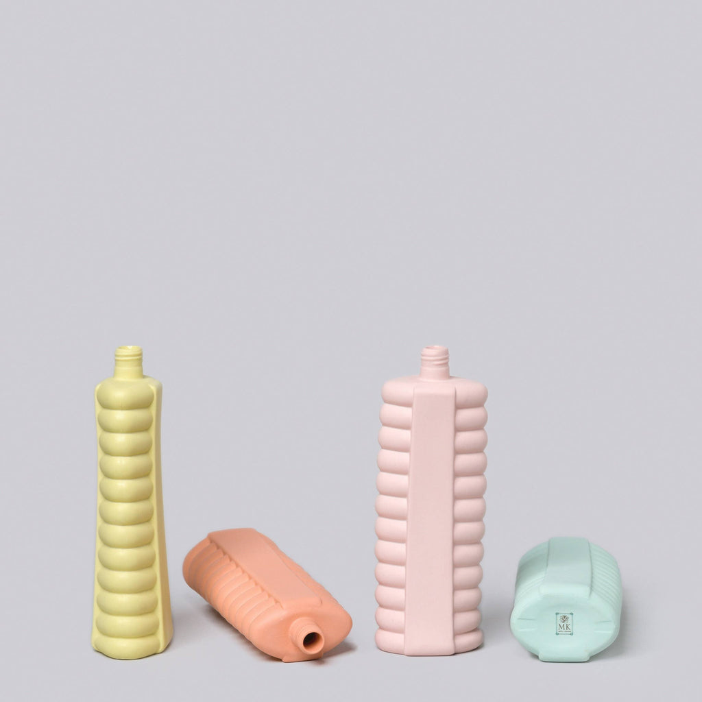 Four colorful ribbed bottles on a light gray background