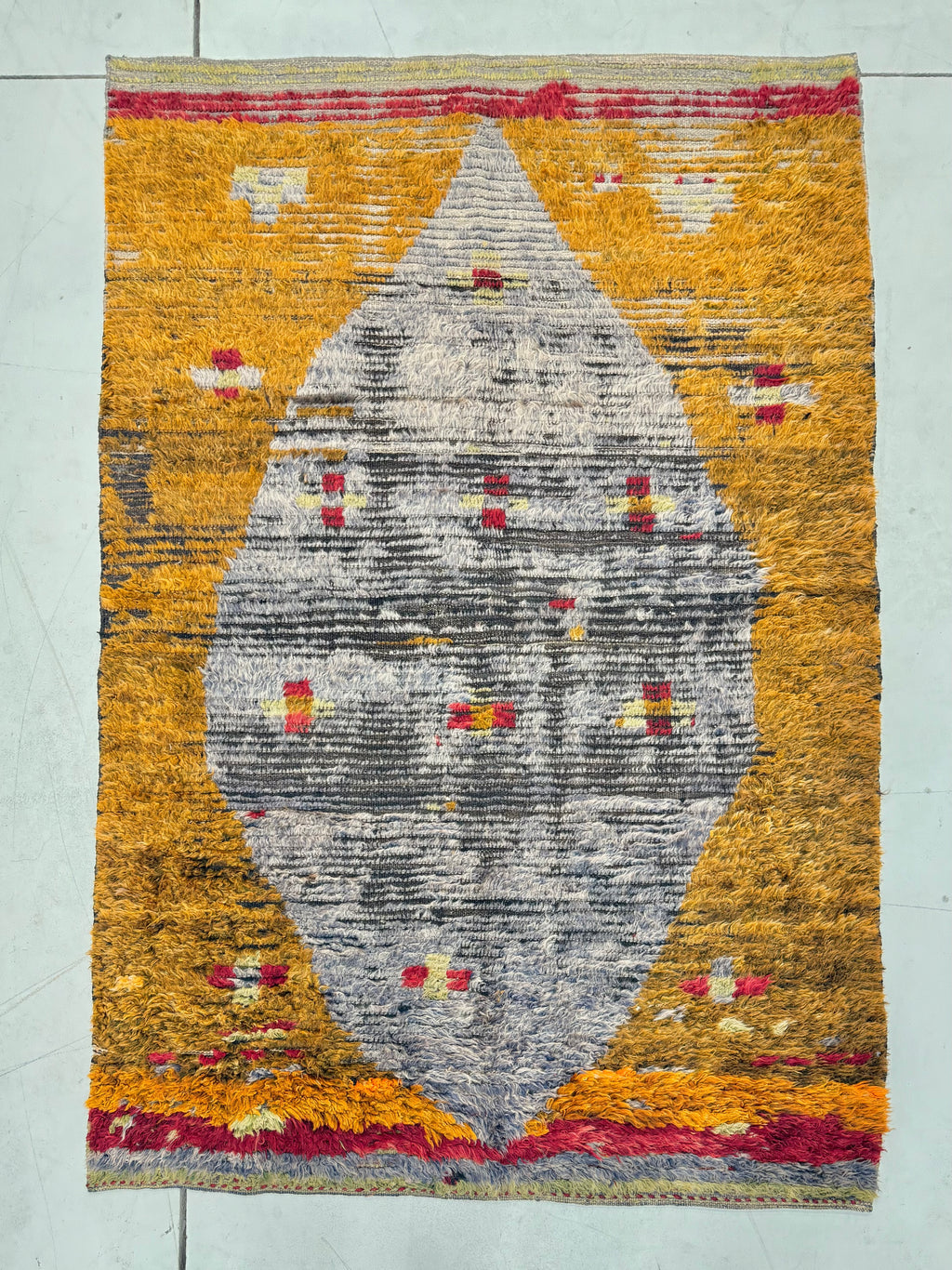 Textile art piece with geometric pattern on a yellow background