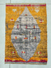 Textile art piece with geometric pattern on a yellow background