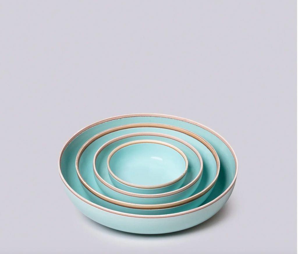 Set of three turquoise ceramic bowls with gold rims on a light gray background