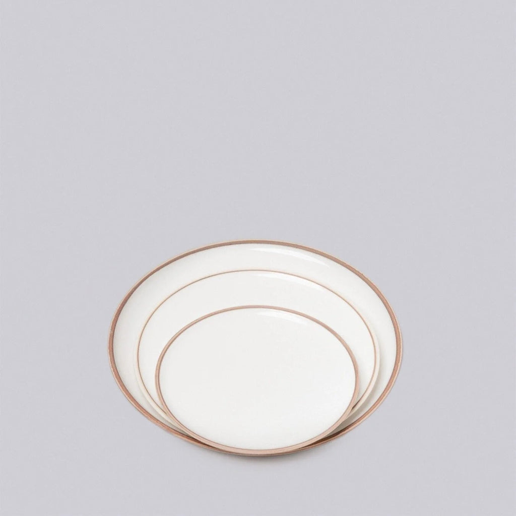 Set of three white plates with gold rims on a light gray background
