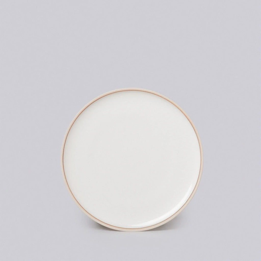 Round ceramic plate with a gold rim on a light gray background