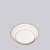 Set of three white plates with gold rims on a light gray background