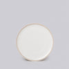 Round ceramic plate with a gold rim on a light gray background