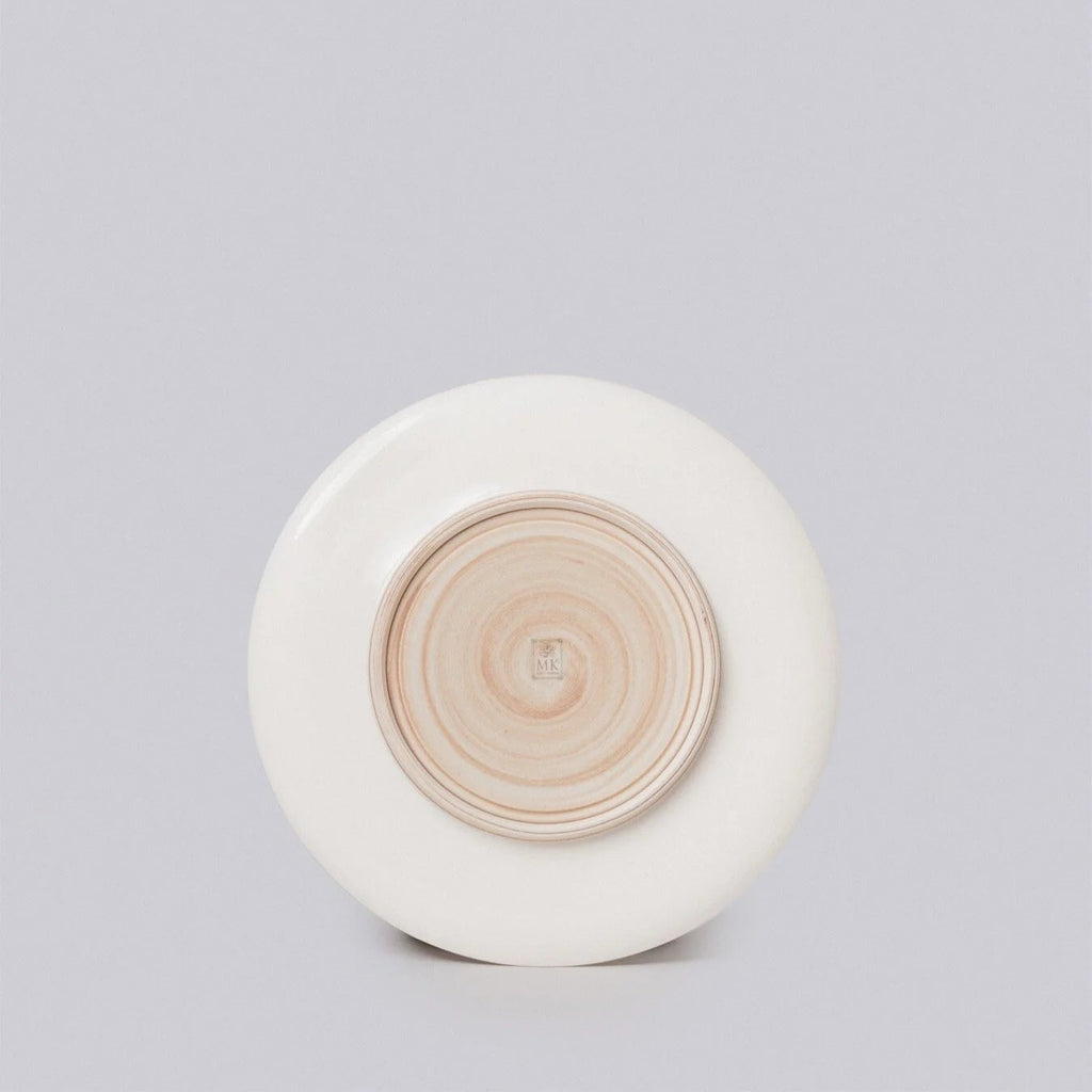 Round ceramic object with concentric circular design on a light gray background
