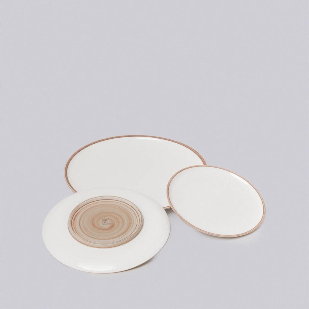 Set of three ceramic plates with gold rims on a light gray background