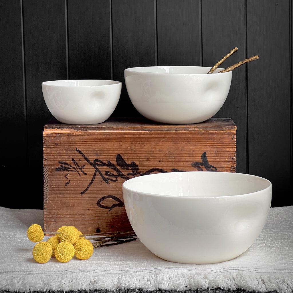 Two white ceramic bowls on a wooden box with yellow decorative elements against a dark background.