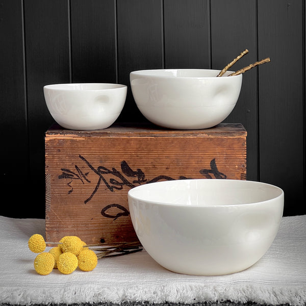 Two white ceramic bowls on a wooden box with yellow decorative elements against a dark background.