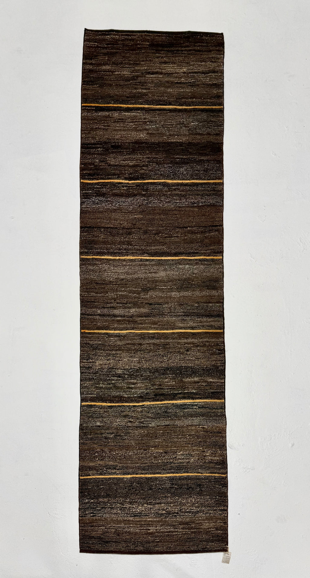Long rectangular brown rug with gold stripes on a white background