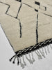 Close-up of a textured rug with geometric pattern and fringe details.
