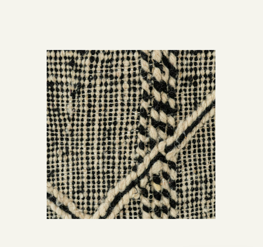 Close-up of a textured fabric with black and white pattern on a light gray background