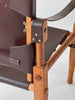 Close-up of a chair with wooden frame and brown leather straps on a white background