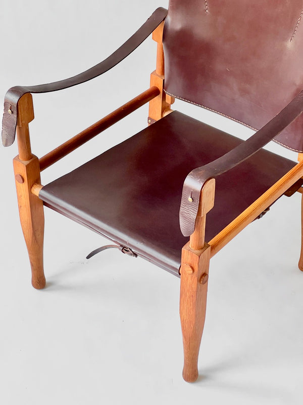Brown leather chair with wooden frame on a light gray background