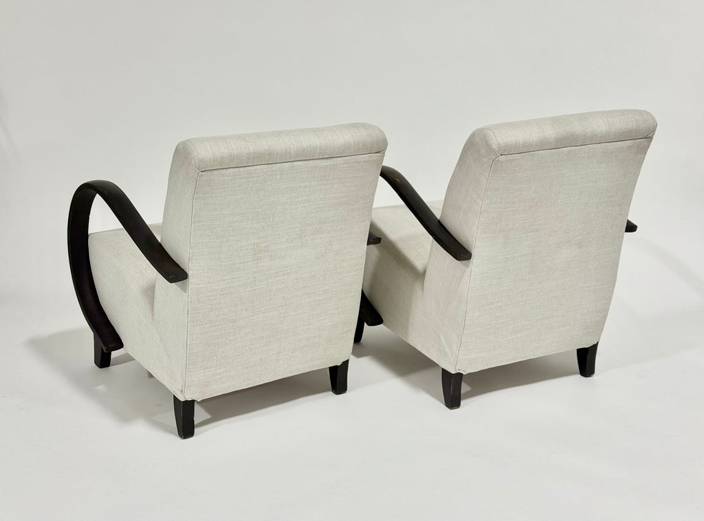Two beige armchairs with black armrests on a white background
