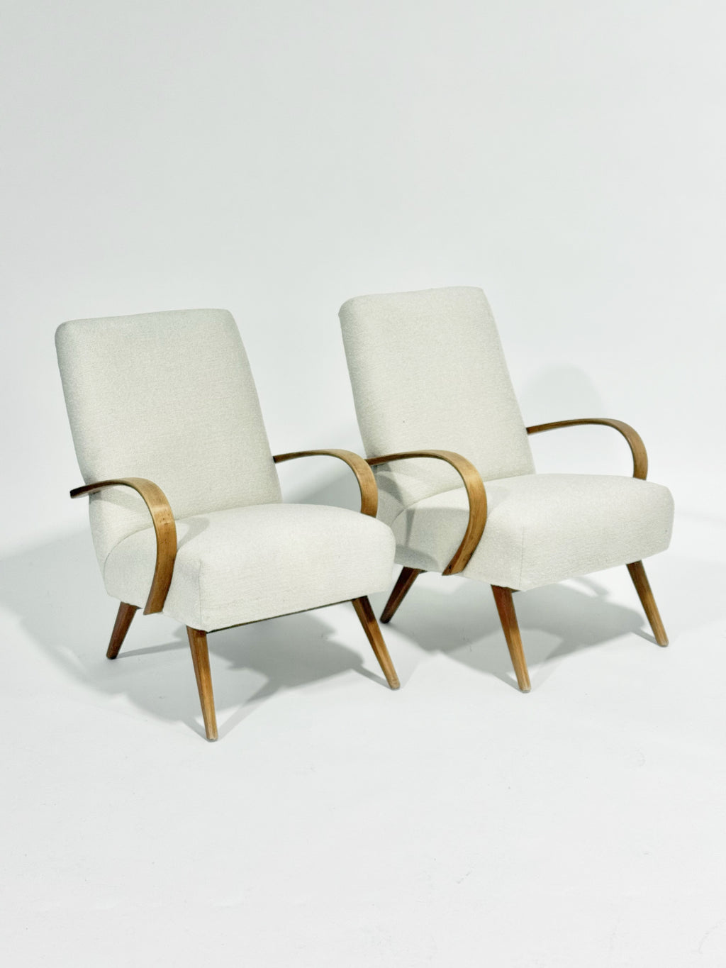 Two white armchairs with wooden frames on a light gray background