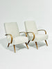 Two white armchairs with wooden frames on a light gray background