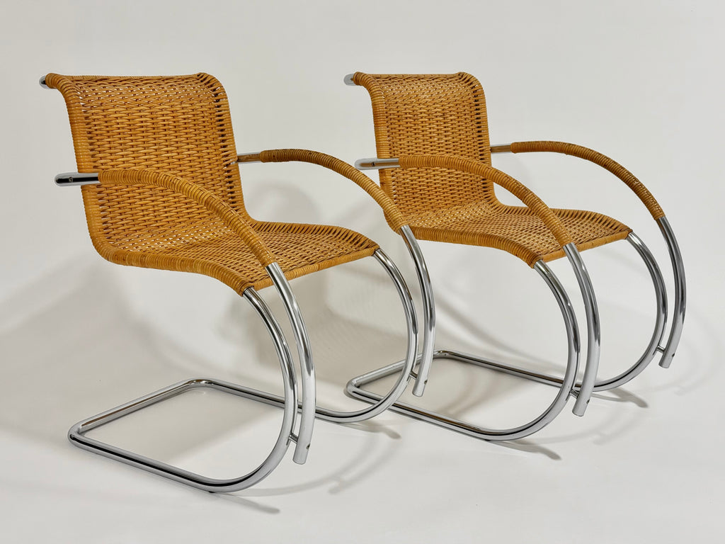 Two wicker chairs with metal frames on a white background