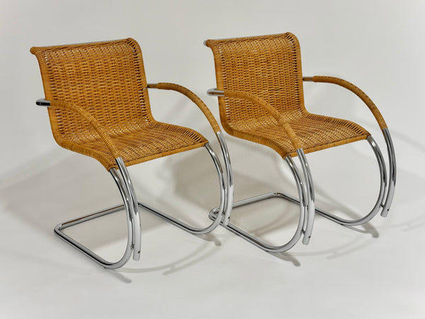 Two wicker chairs with metal frames on a white background