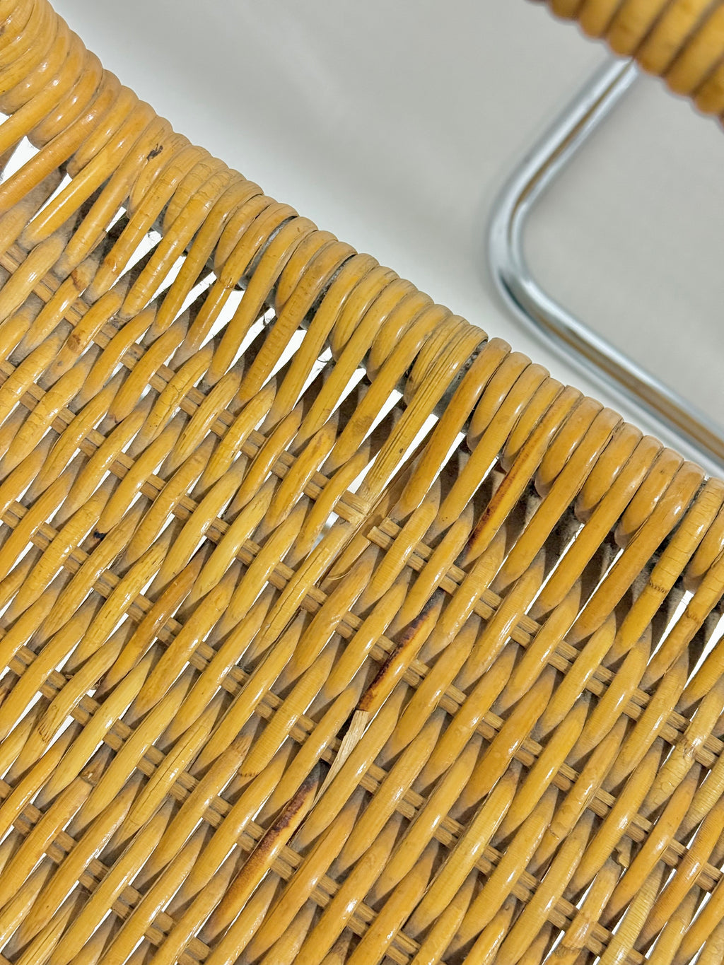 Close-up of a wicker chair with a metal frame on a white background