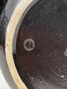 Close-up of a dark brown ceramic vase with a circular logo on a light beige rim.