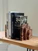 Wooden bookends holding books on a shelf against a neutral background