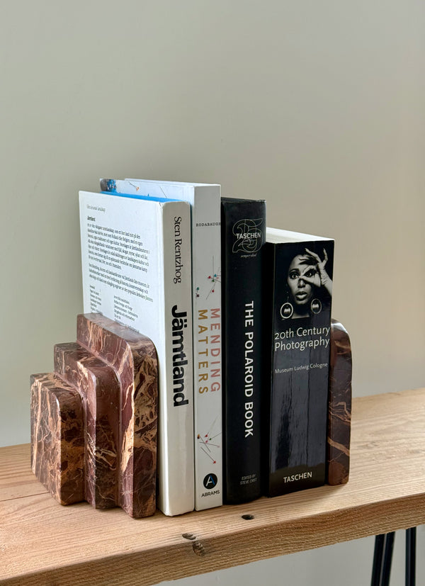 Marble bookends holding books on a wooden surface with a neutral background