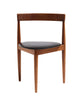 A mid-century modern wooden dining chair with a warm brown wood frame and a black upholstered seat cushion, shown against a plain white background.