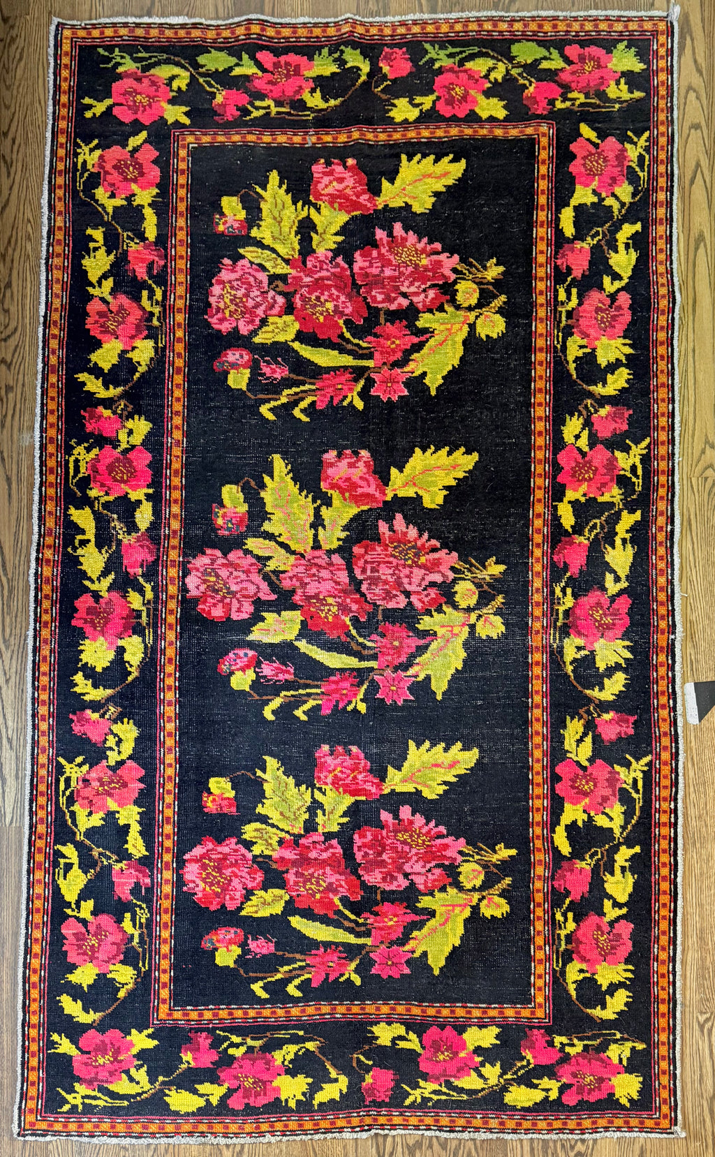 Floral patterned rug with pink and yellow flowers on a black background
