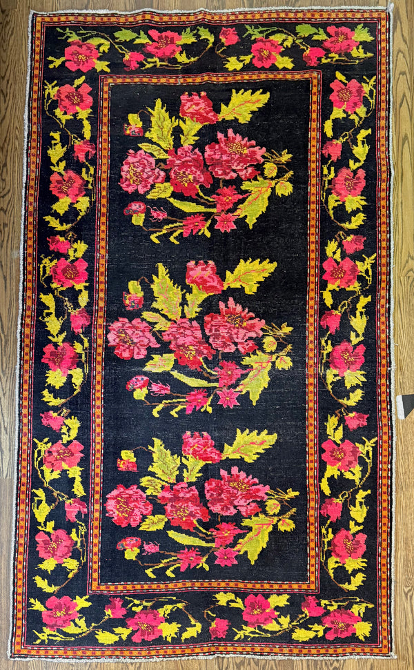 Floral patterned rug with pink and yellow flowers on a black background