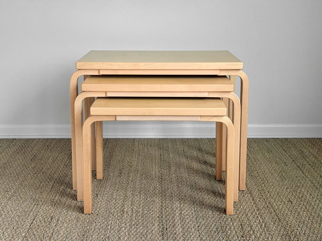 Set of four wooden nesting tables on a carpeted floor with a plain wall background