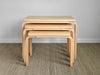 Set of four wooden nesting tables on a carpeted floor with a plain wall background