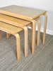 Set of three wooden nesting tables on a carpeted floor.