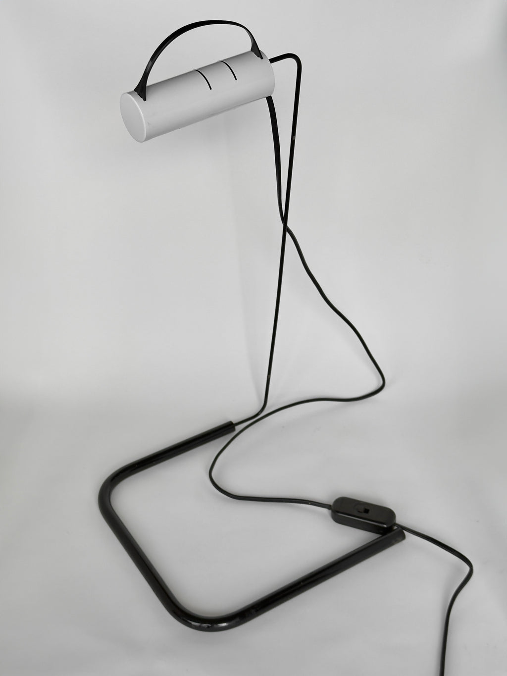 Modern desk lamp with a white cylindrical shade and black metal base on a light gray background