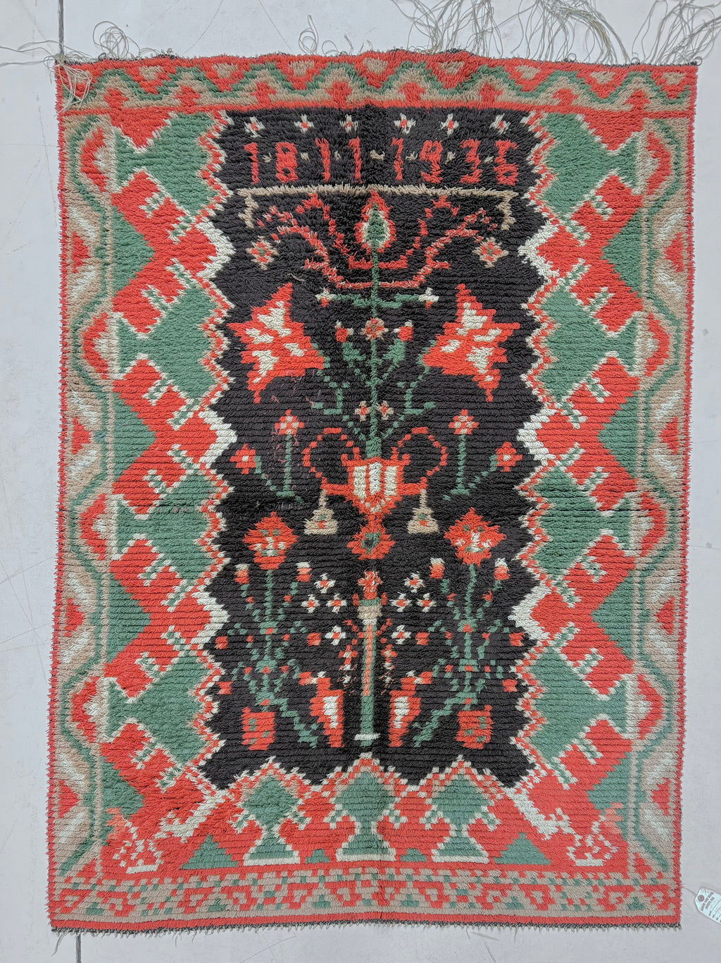 Traditional woven rug with geometric patterns and central design on a plain background