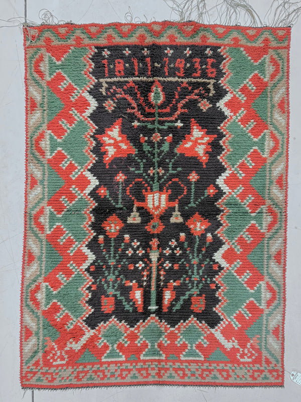 Traditional woven rug with geometric patterns and central design on a plain background