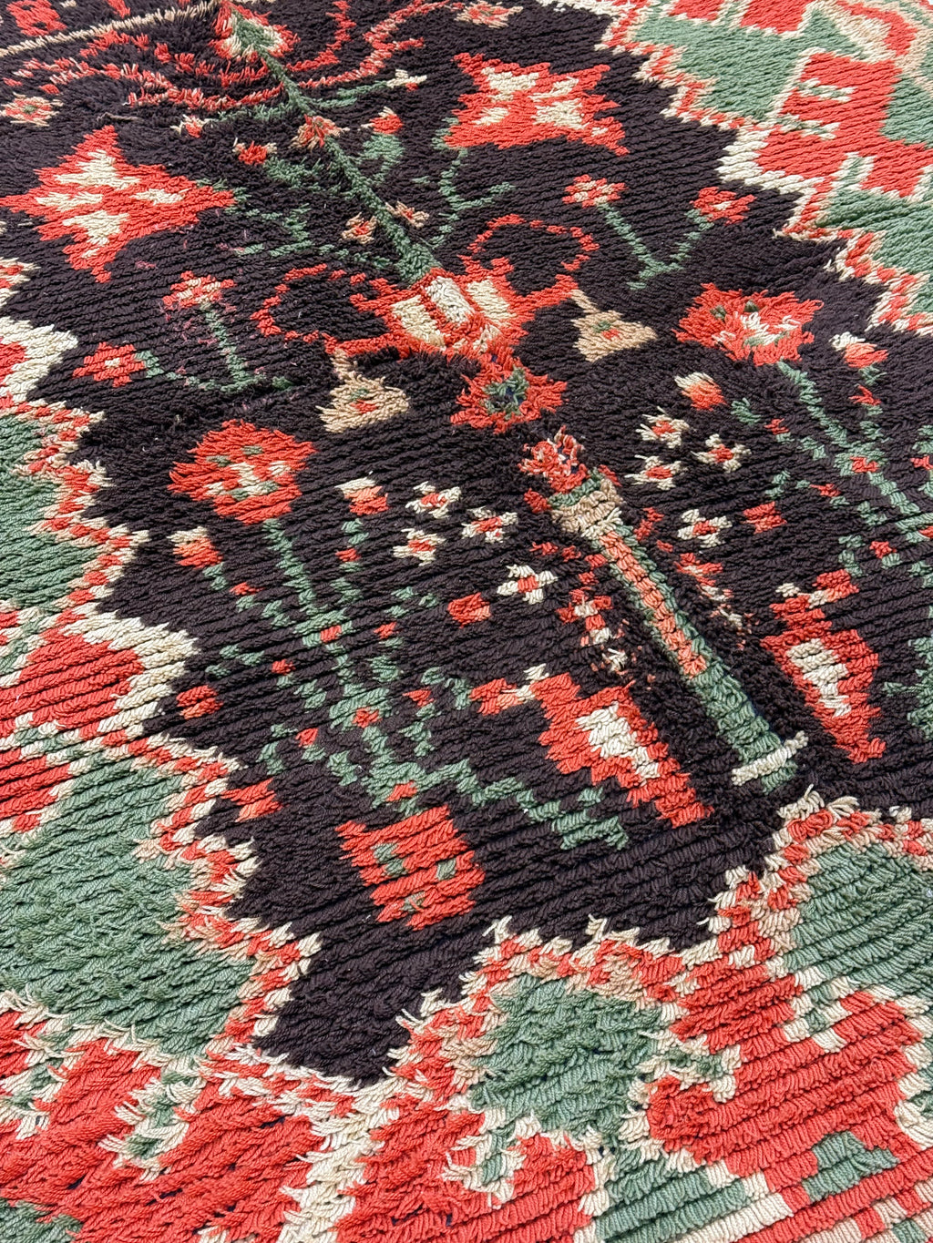 Close-up of a patterned fabric with red, green, and black colors. Tapestry art