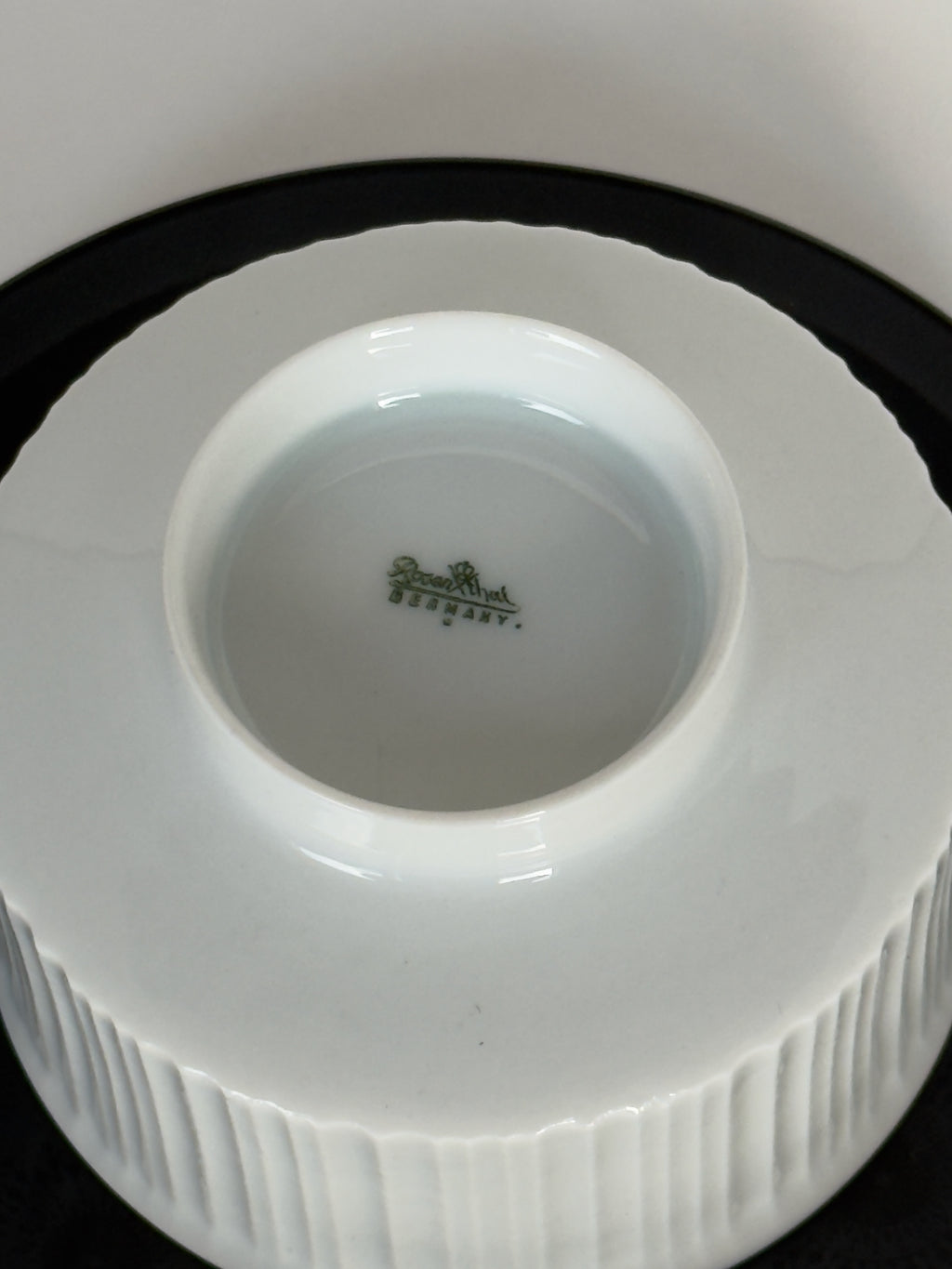 Close-up of a white ceramic product with a visible brand logo on a black background